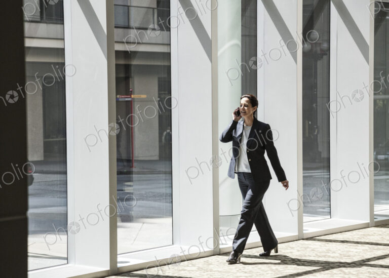 Businesswoman on the phone and walking through the lobby of a large business center.