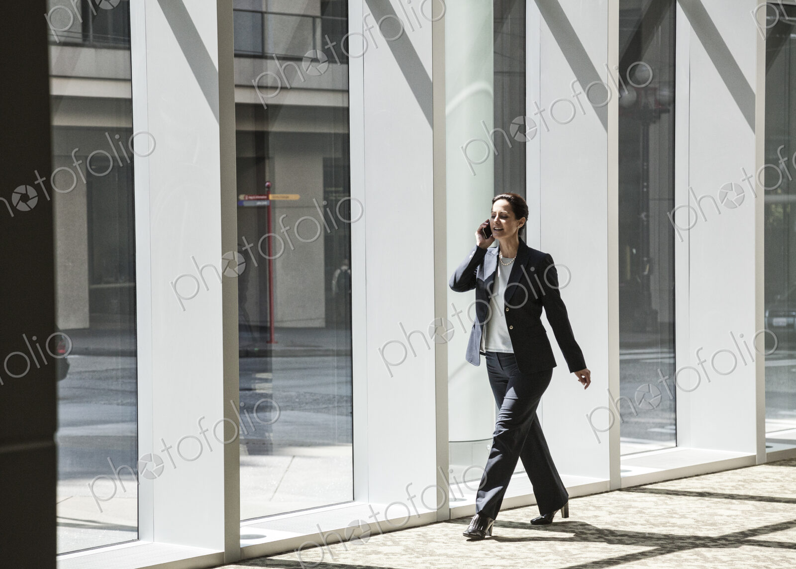 Businesswoman on the phone and walking through the lobby of a large business center.