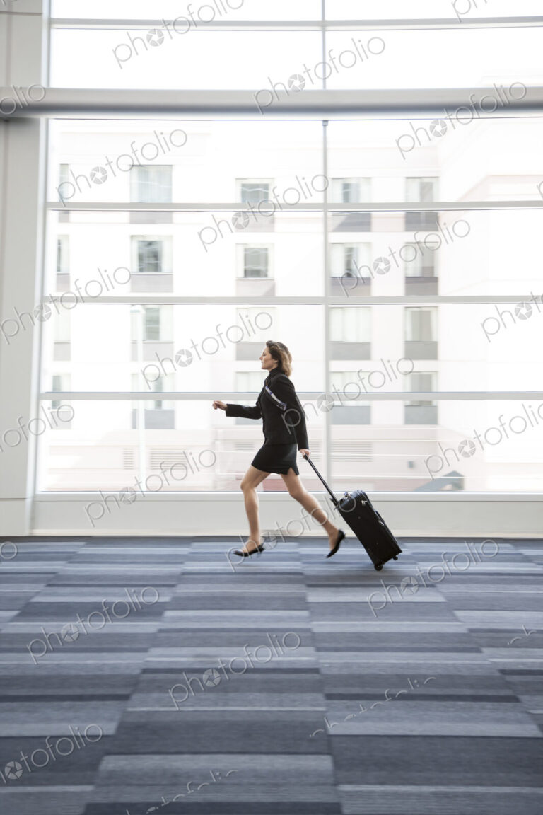 Businesswoman running through a conference centre lobby.