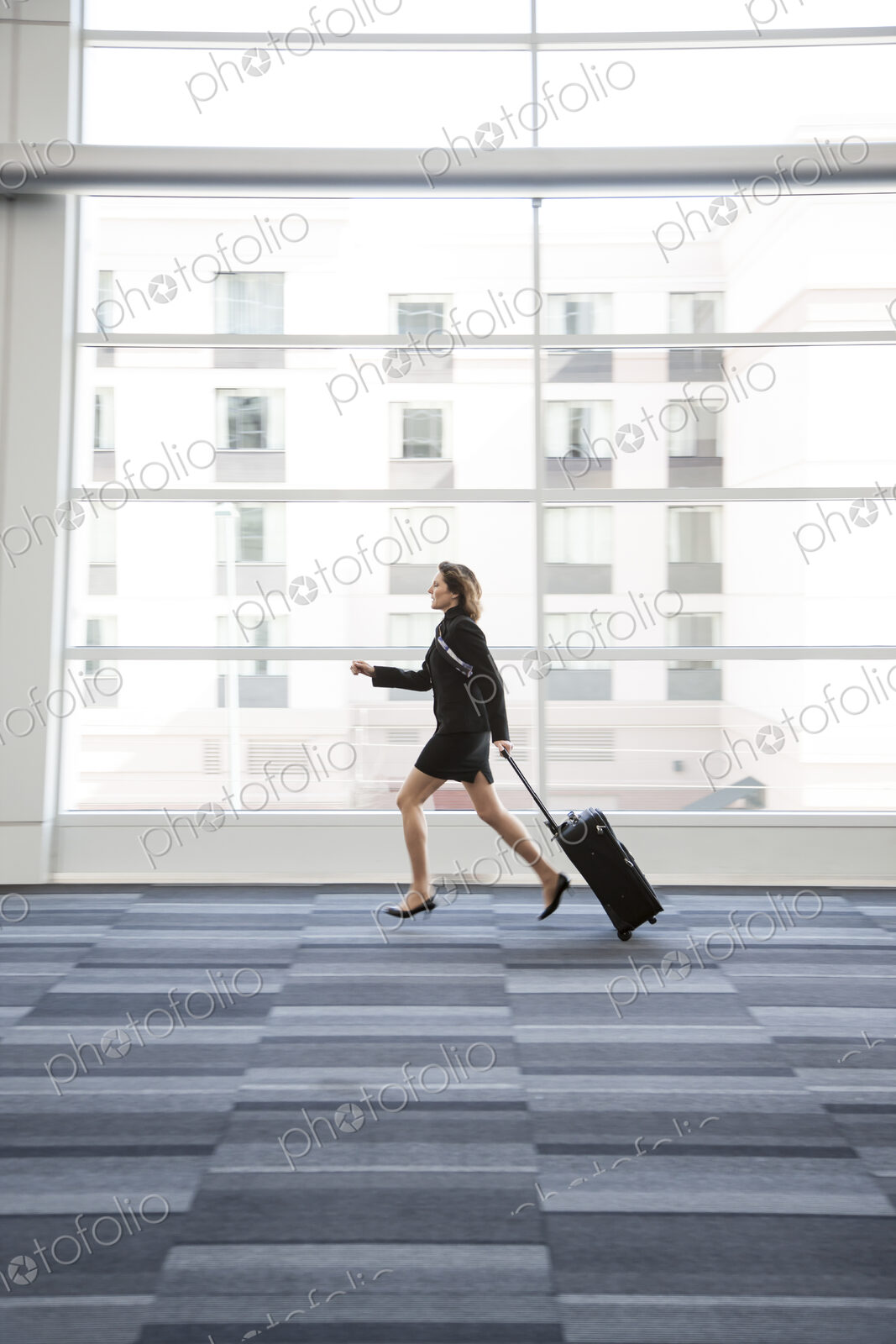 Businesswoman running through a conference centre lobby.