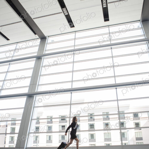 Businesswoman running through a conference centre lobby. Businesswoman running through a conference centre lobby.