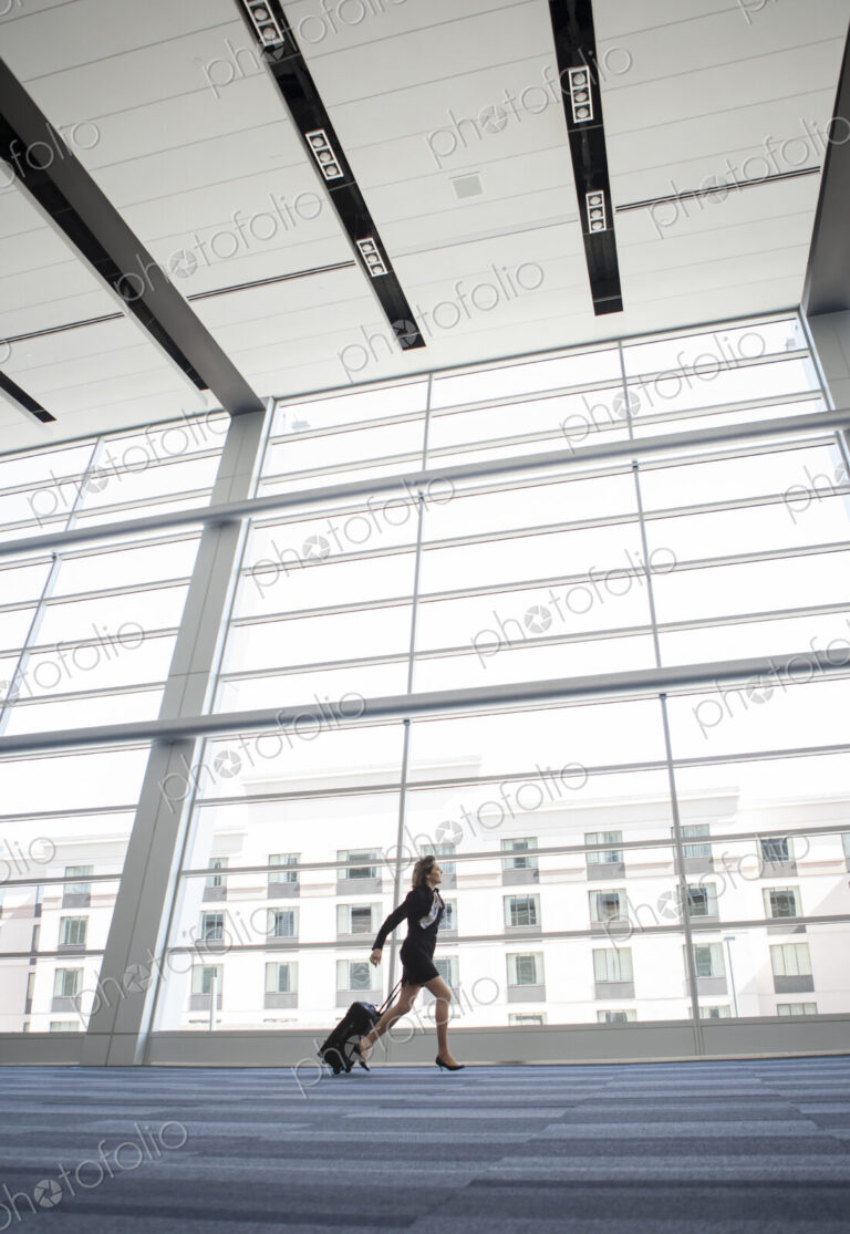 Businesswoman running through a conference centre lobby.