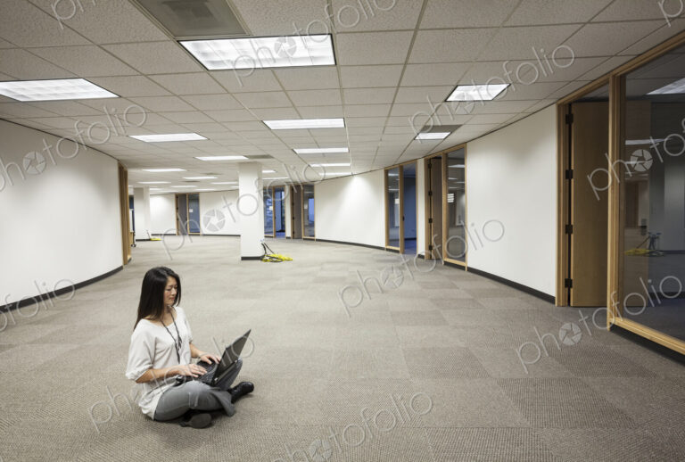 Businesswoman sitting working on a laptop computer in the middle of an empty office