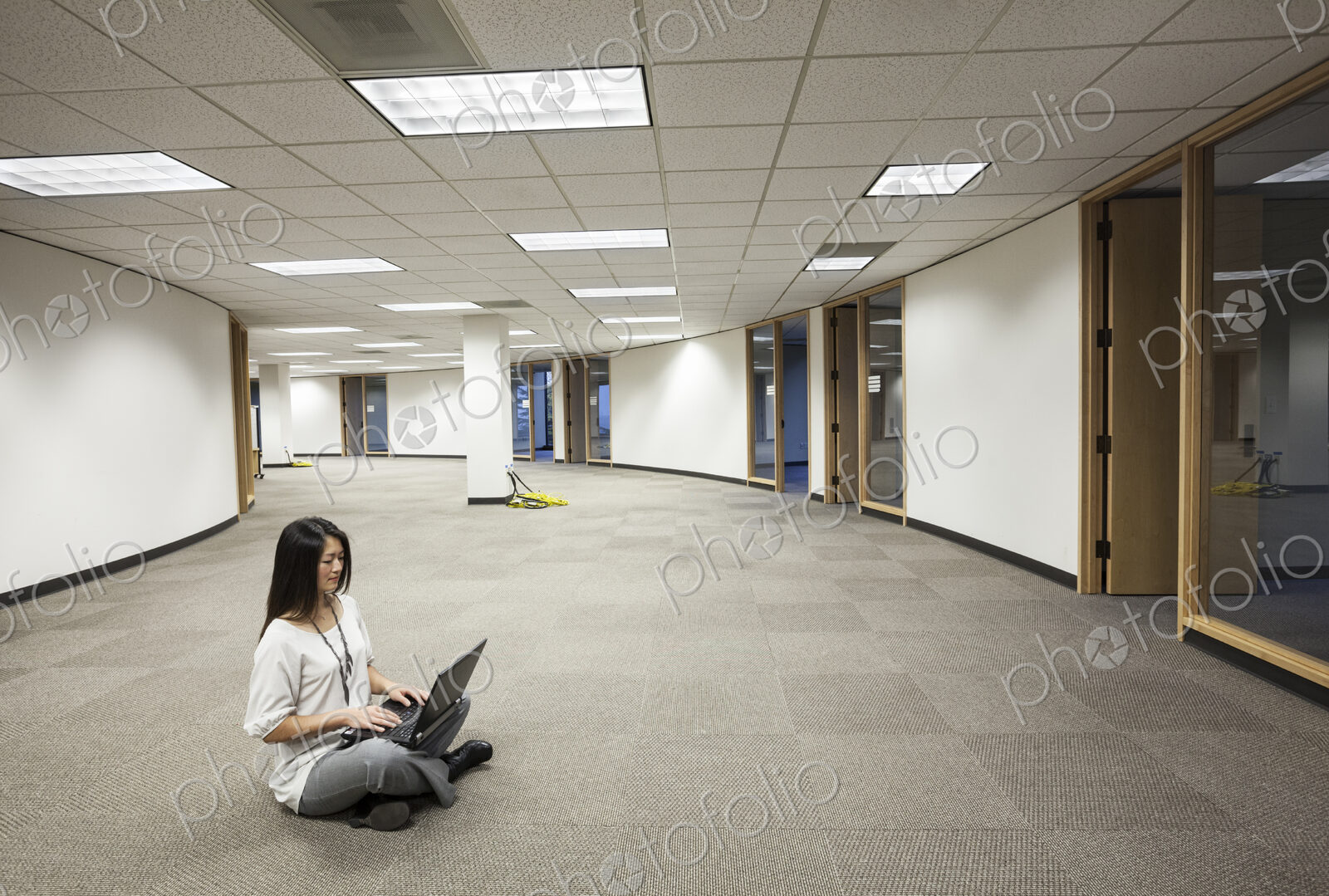 Businesswoman sitting working on a laptop computer in the middle of an empty office