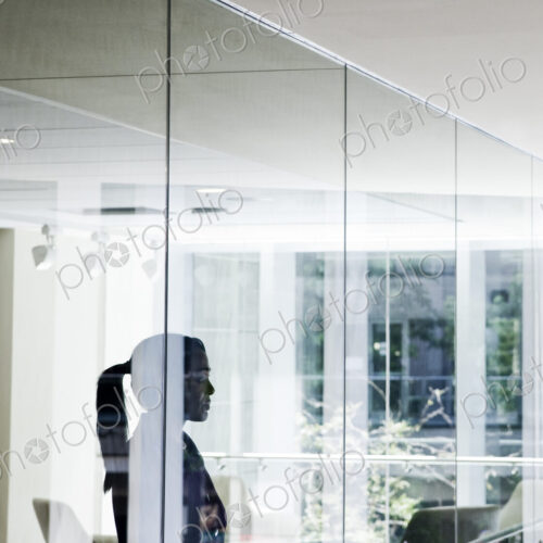 Businesswoman standing in a conference room window in a large business center. Businesswoman standing in a conference room window in a large business center.