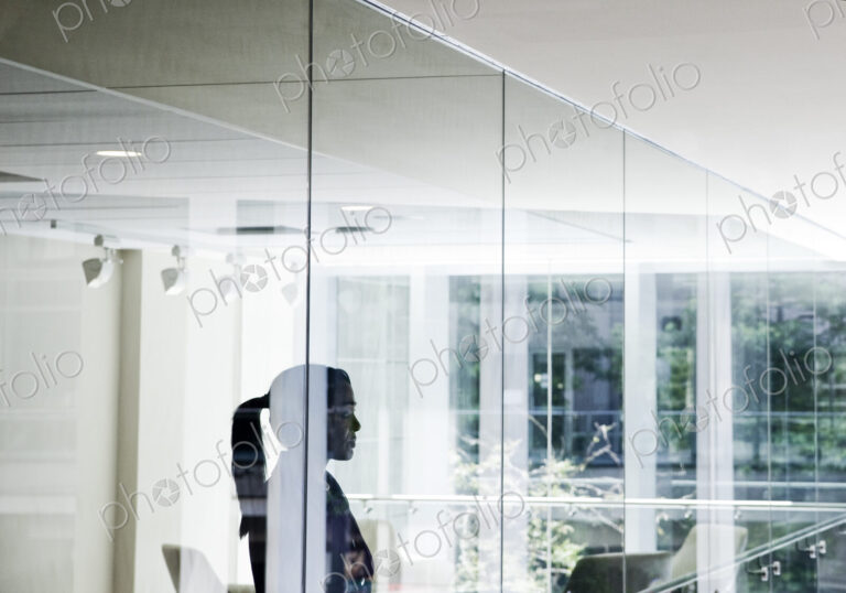 Businesswoman standing in a conference room window in a large business center.