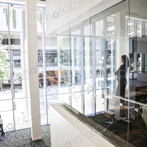 Businesswoman standing in a conference room window in a large business center.