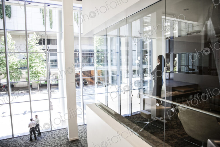 Businesswoman standing in a conference room window in a large business center.