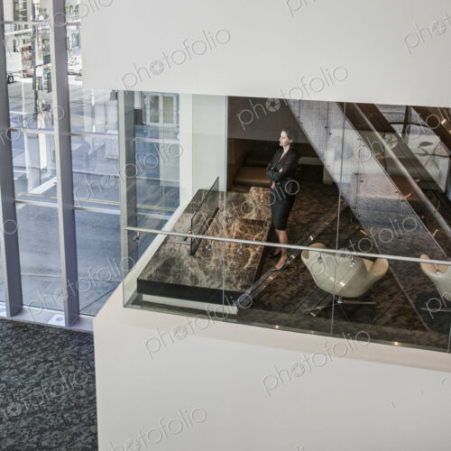 Businesswoman standing in a conference room window in a large business center.