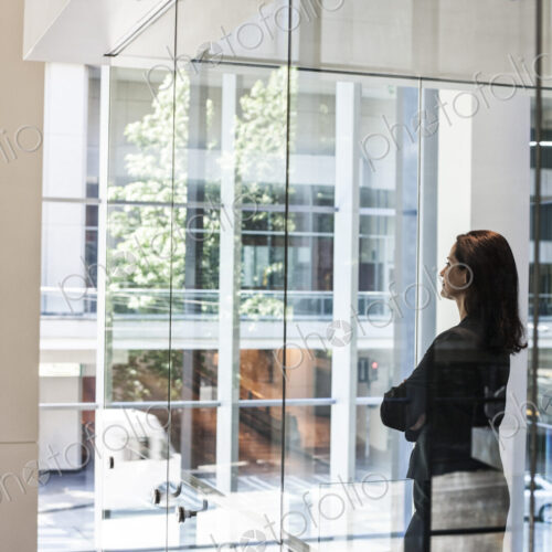 Businesswoman standing in a conference room window in a large business center.
