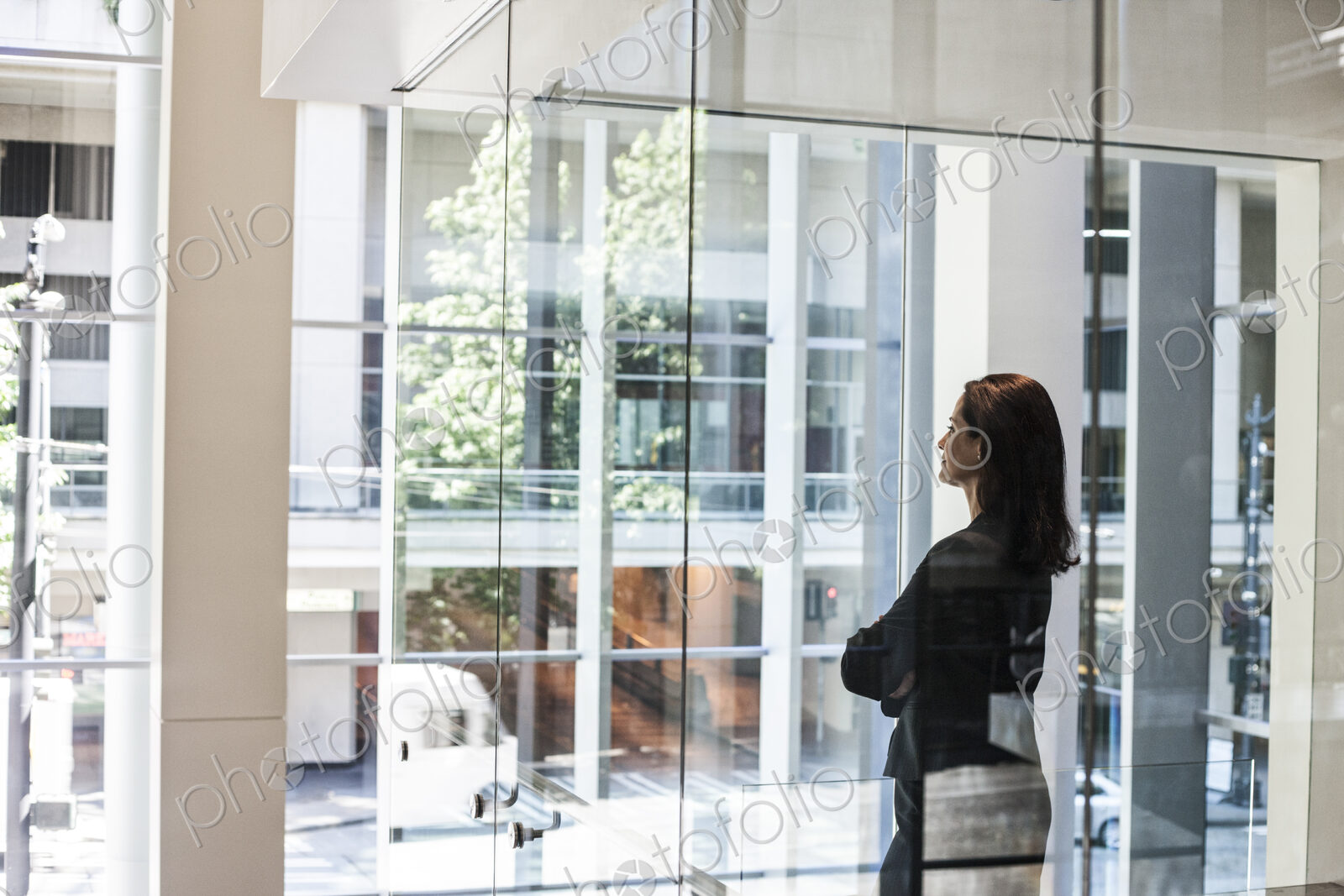 Businesswoman standing in a conference room window in a large business center.