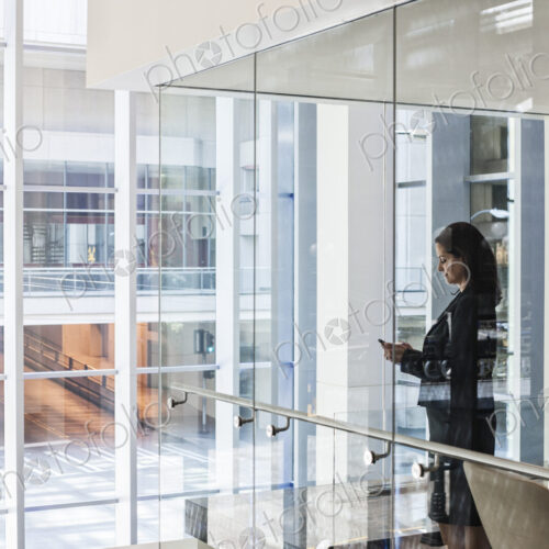 Businesswoman standing in a conference room window in a large business center.