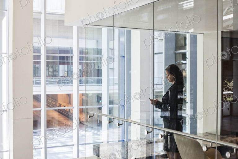 Businesswoman standing in a conference room window in a large business center.