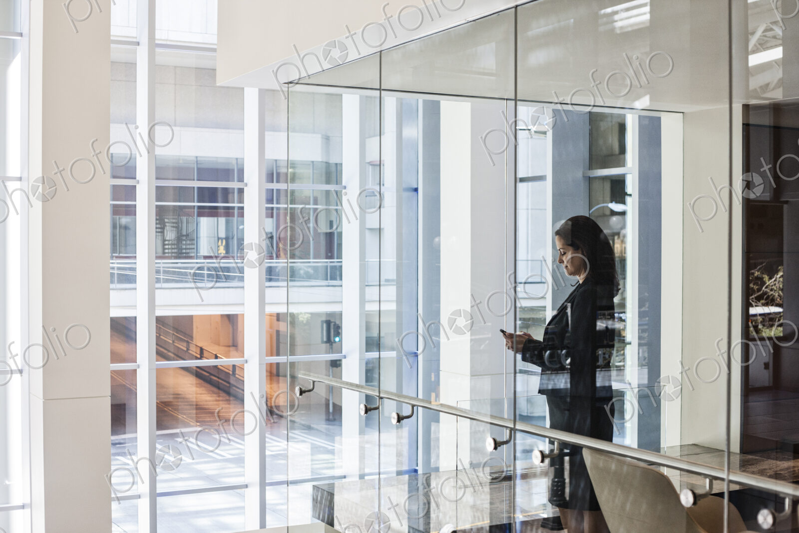 Businesswoman standing in a conference room window in a large business center.