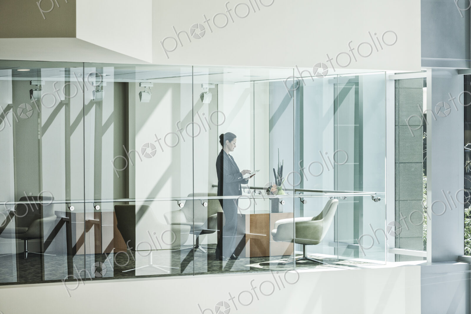 Businesswoman standing in a conference room window in a large business center.