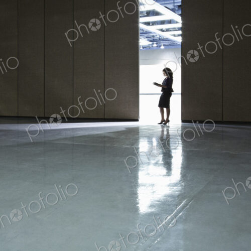 Businesswoman standing in a doorway between rooms in a convention center arena. Businesswoman standing in a doorway between rooms in a convention center arena.