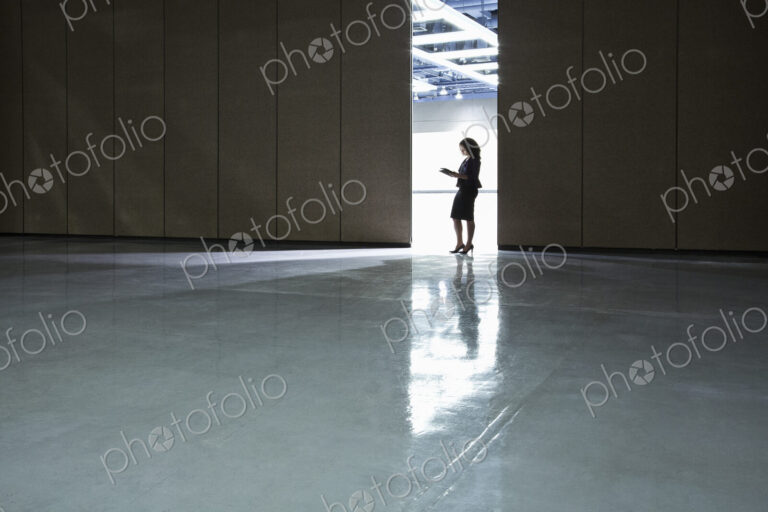 Businesswoman standing in a doorway between rooms in a convention center arena.
