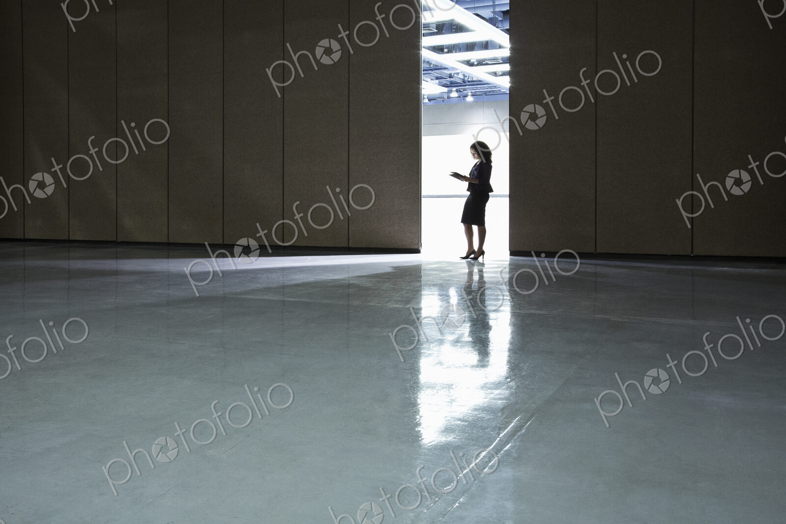 Businesswoman standing in a doorway between rooms in a convention center arena.