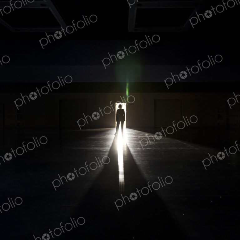 Businesswoman standing in the open doorway of a convention center arena.