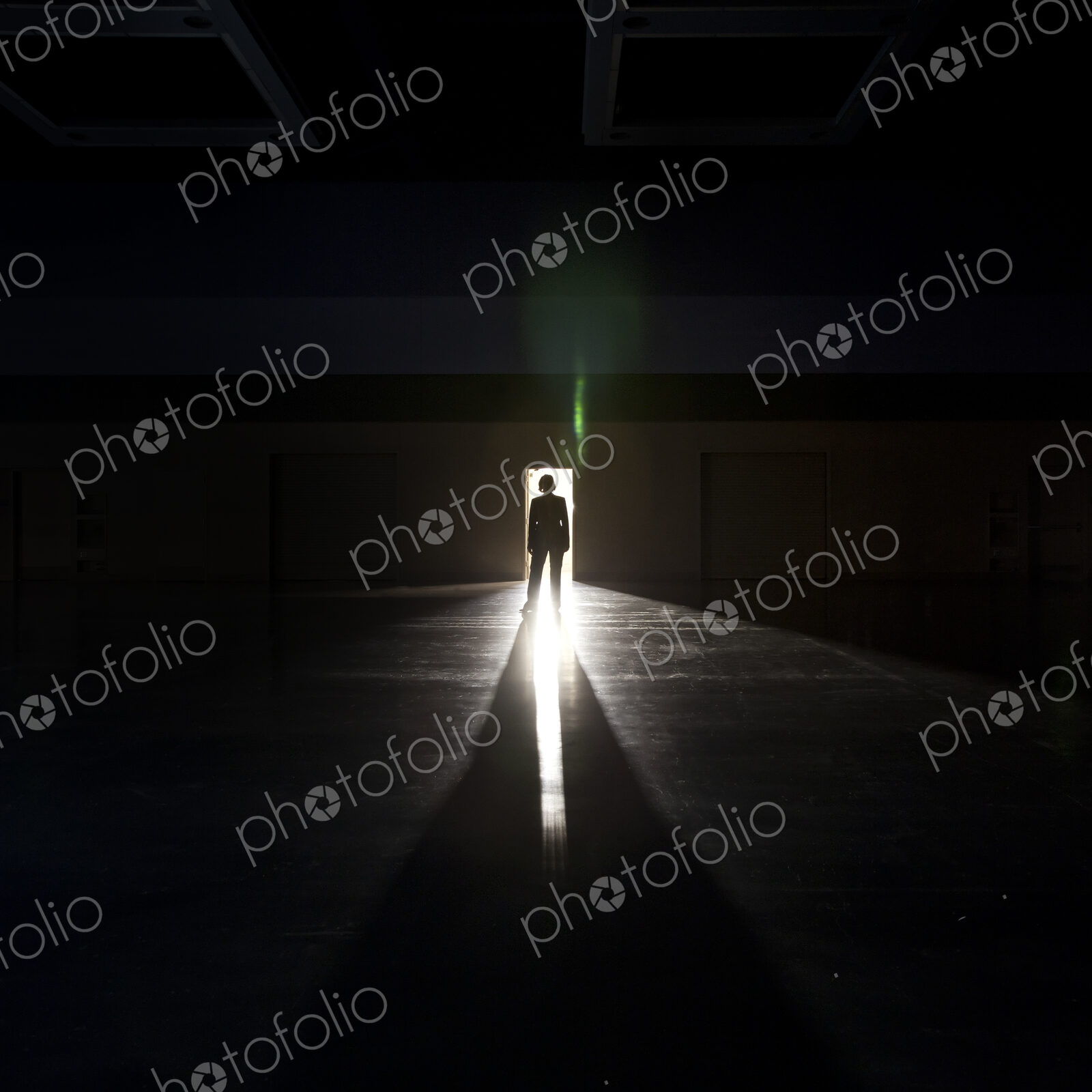 Businesswoman standing in the open doorway of a convention center arena.