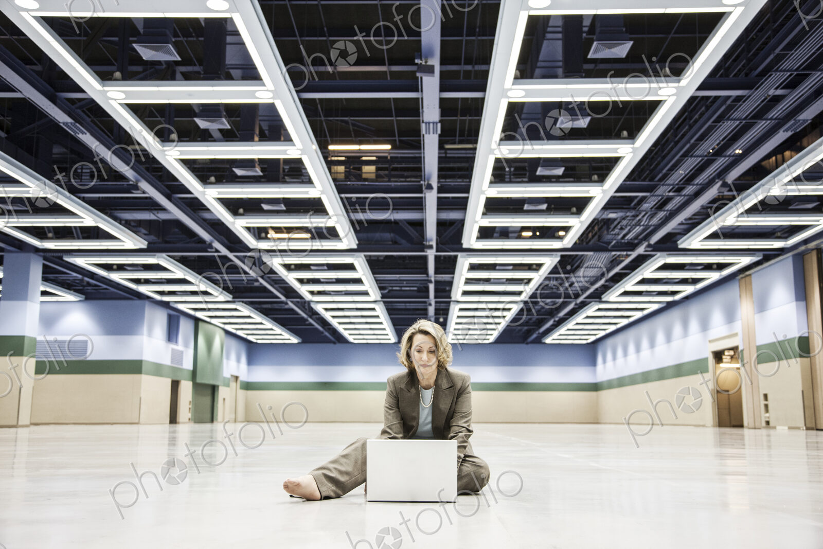 Businesswoman working on a laptop sitting on the floor of a convention center