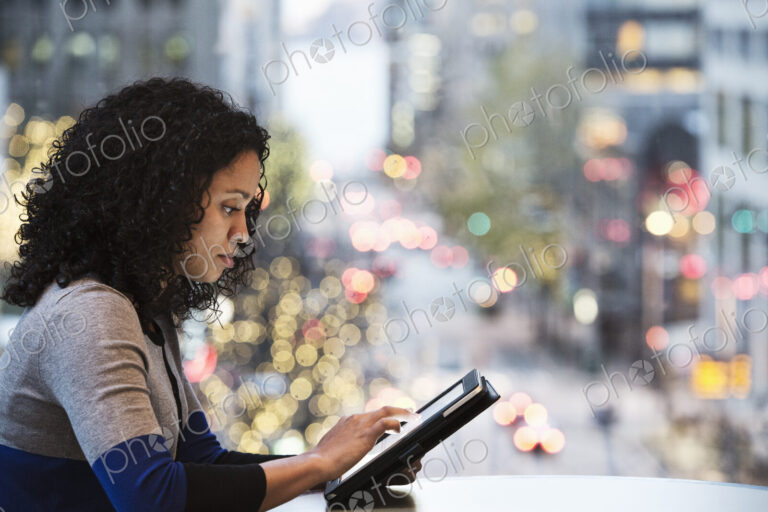 Businesswoman working on a notebook computer by a window with a city view