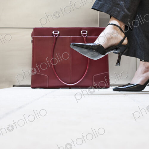 Businesswoman's feet in high heeled shoes and her purse.
