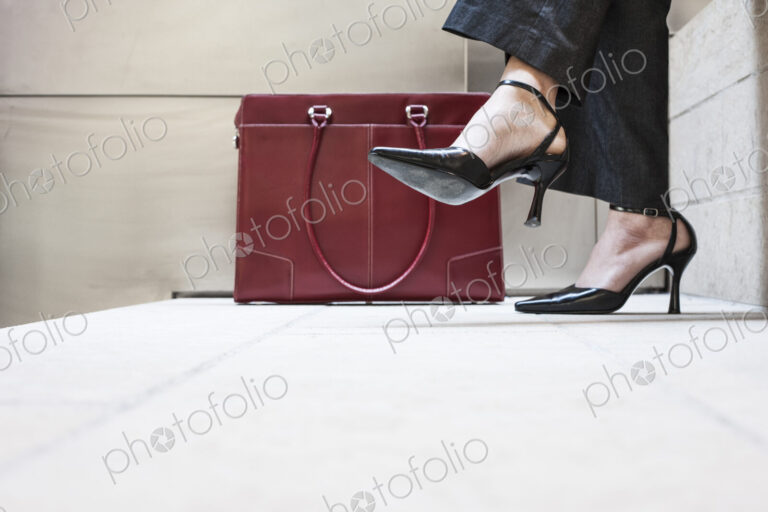 Businesswoman's feet in high heeled shoes and her purse.
