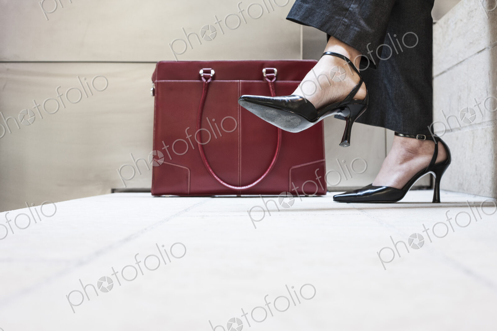 Businesswoman’s feet in high heeled shoes and her purse.