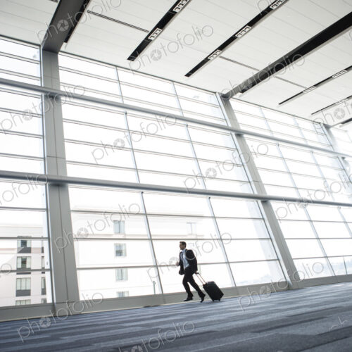 Bussinessman running past a window in the lobby of a conference centre. Bussinessman running past a window in the lobby of a conference centre.