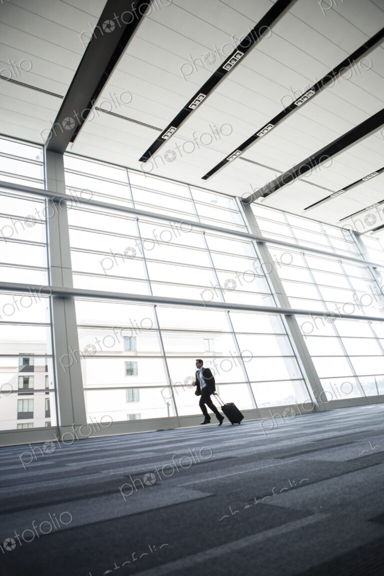 Bussinessman running past a window in the lobby of a conference centre.