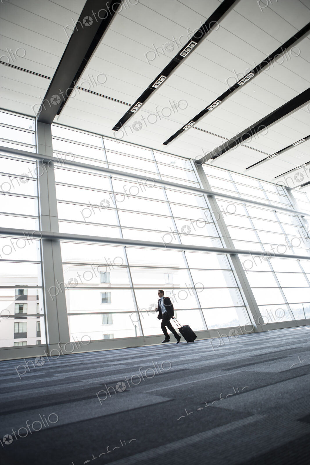 Bussinessman running past a window in the lobby of a conference centre.