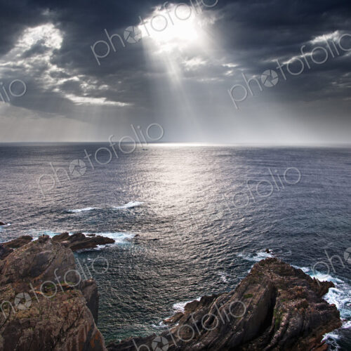Cabo Sardao coastline in Portugal. Sun streaming through cloud on to the sea.