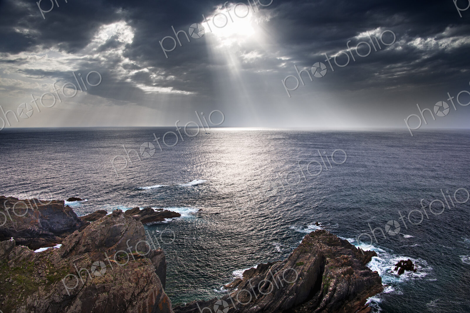 Cabo Sardao coastline in Portugal. Sun streaming through cloud on to the sea.