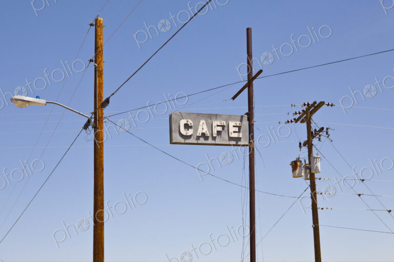 Cafe sign high on a pole, electricity and telephone wiring on posts.