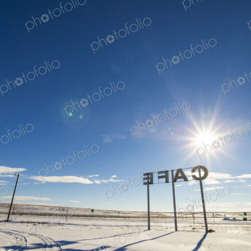 Cafe sign, large letters and a shadow on the ground.