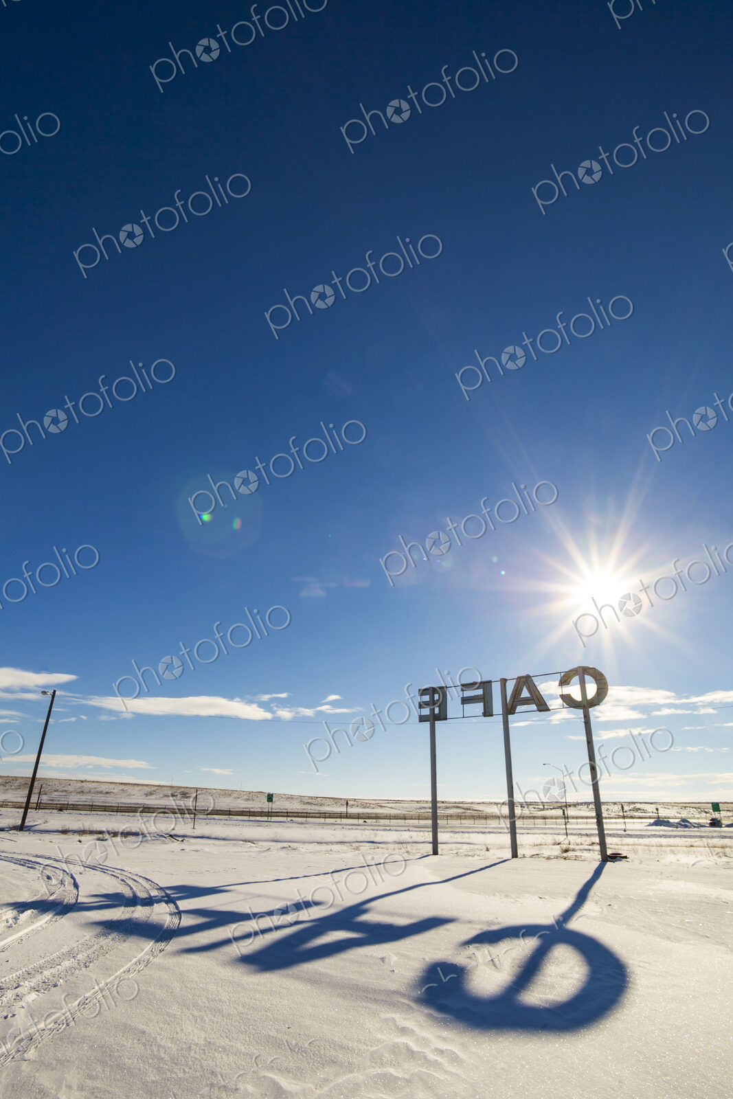 Cafe sign, large letters and a shadow on the ground.