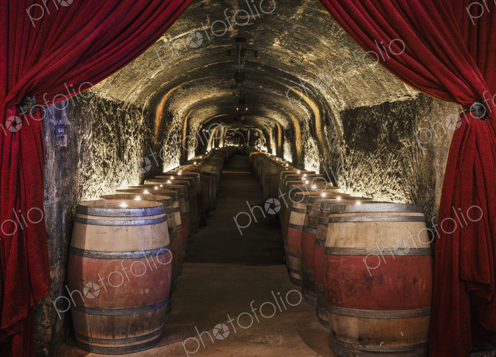 Candles on wine barrels in cave cellar