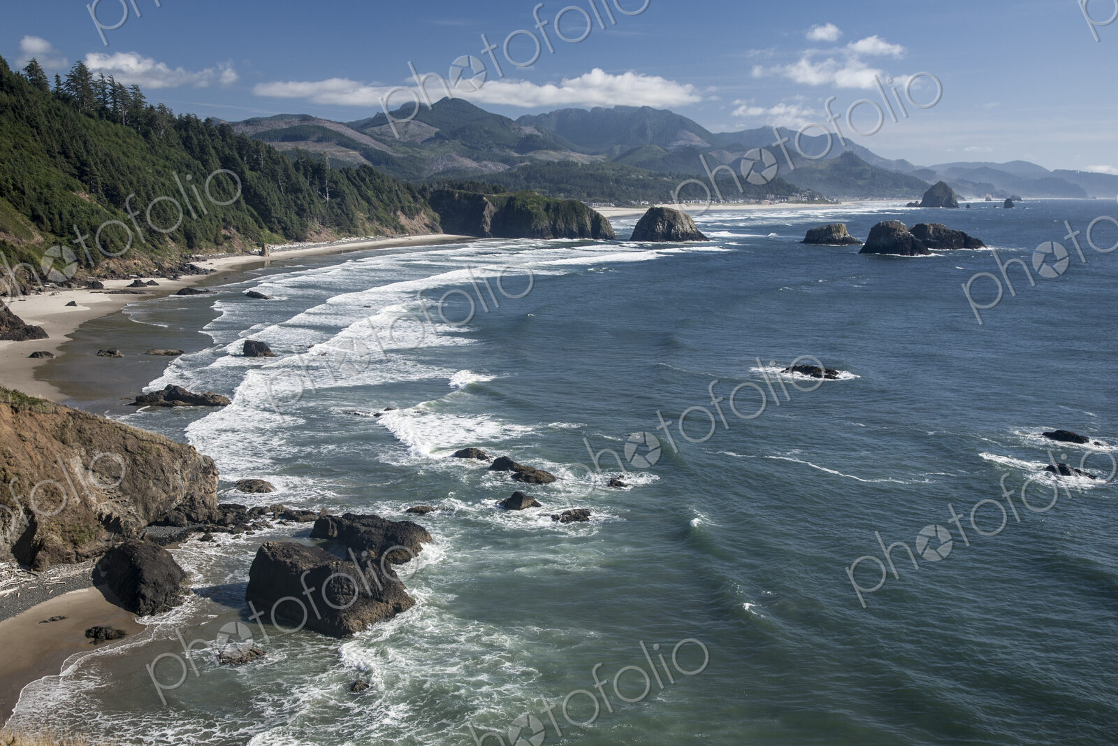 Cannon Beach with waves breaking on rocky shoreline from above.
