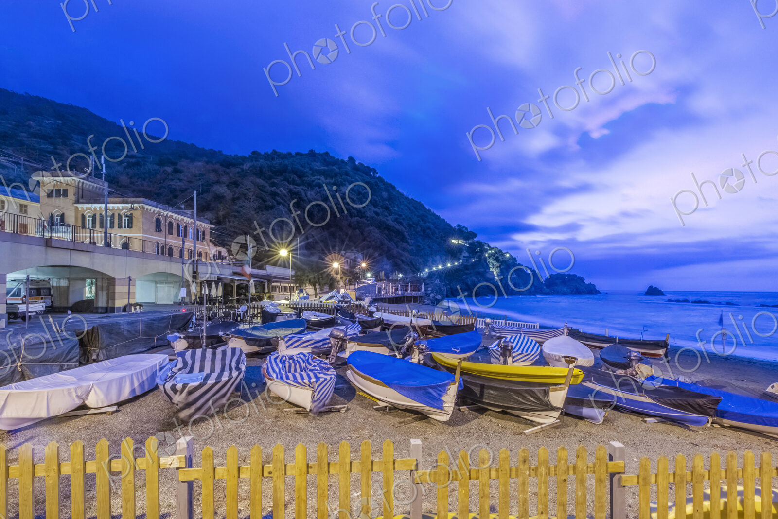Canoes docked on beach under Monterosso al Mare cityscape, La Spezia, Italy
