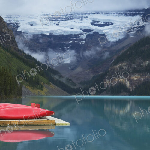 Canoes on wooden dock over still remote lake Canoes on wooden dock over still remote lake