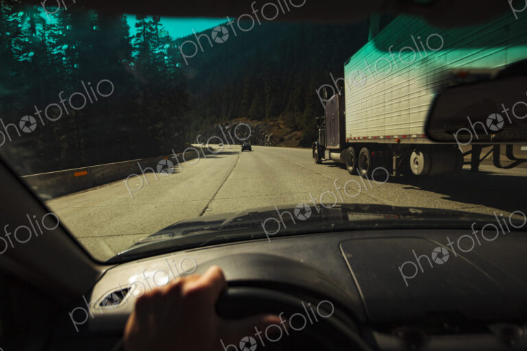 Car driver's windshield pov of multi-lane mountain highway with a semi truck,…