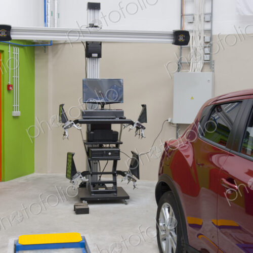 Car in a workshop and a computer running diagnostics on the engine.