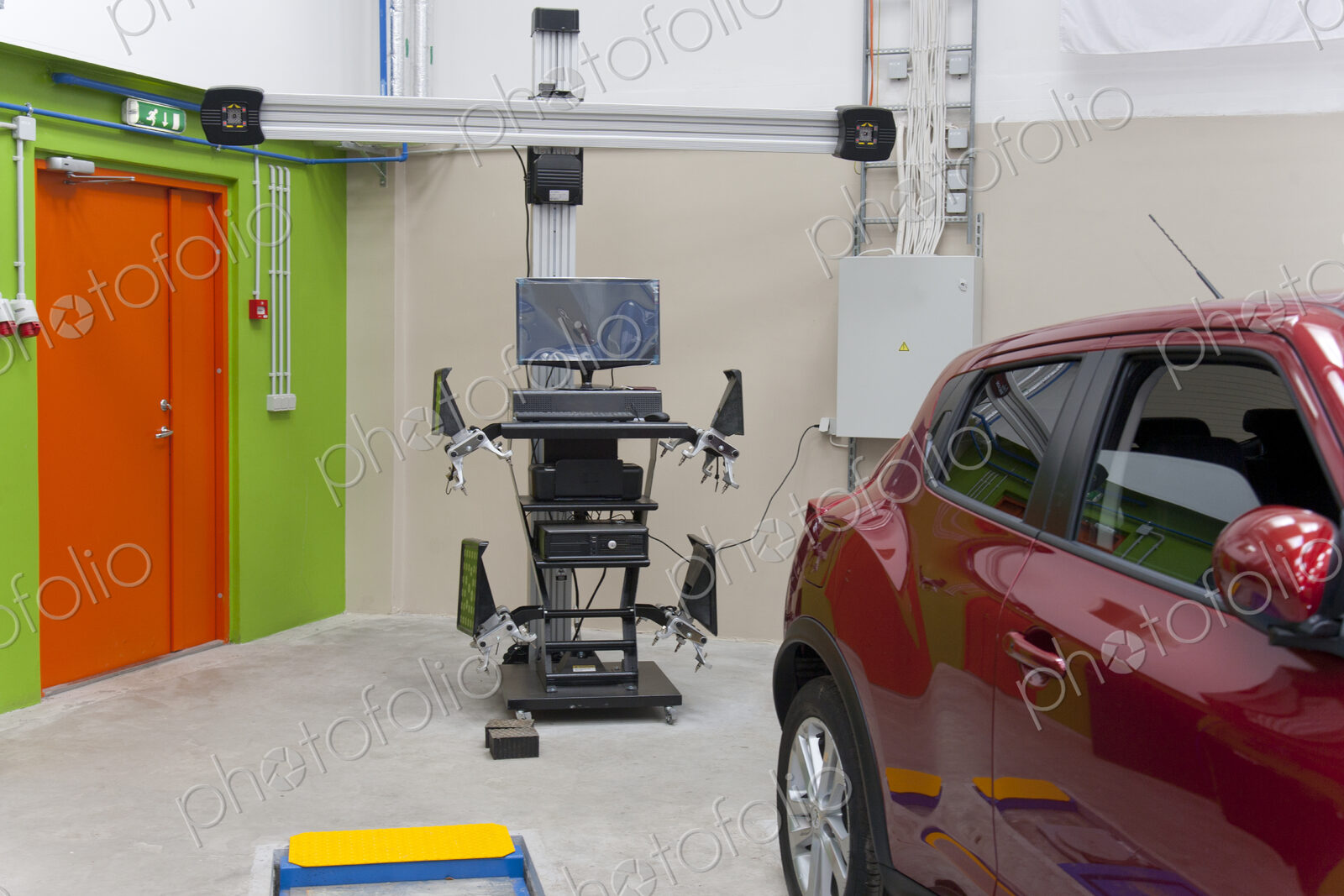 Car in a workshop and a computer running diagnostics on the engine.