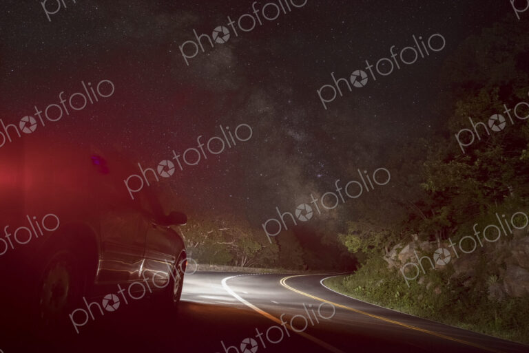 Car on winding road under starry sky