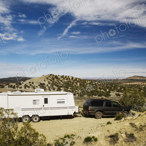 Car pulling trailer in desert landscape, Grand Staircase Escalante, Utah, United States