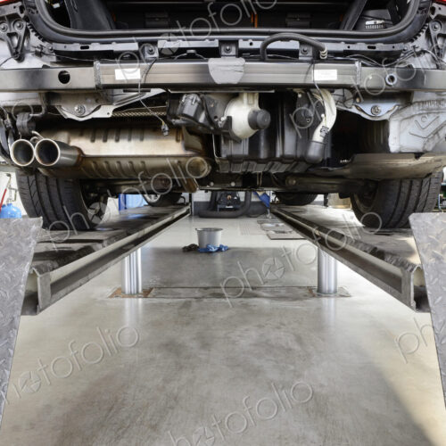 Car under repair on a service ramp or lift in an auto repair workshop.