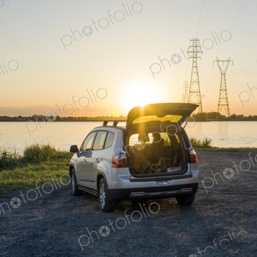 Car with open trunk looking out over a lake or inlet at sunset. Car with open trunk looking out over a lake or inlet at sunset.
