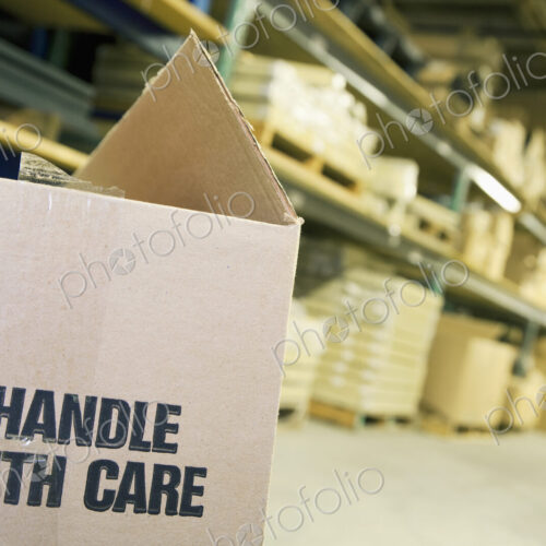 Carboard box in warehouse with shelves behind. Carboard box in warehouse with shelves behind.