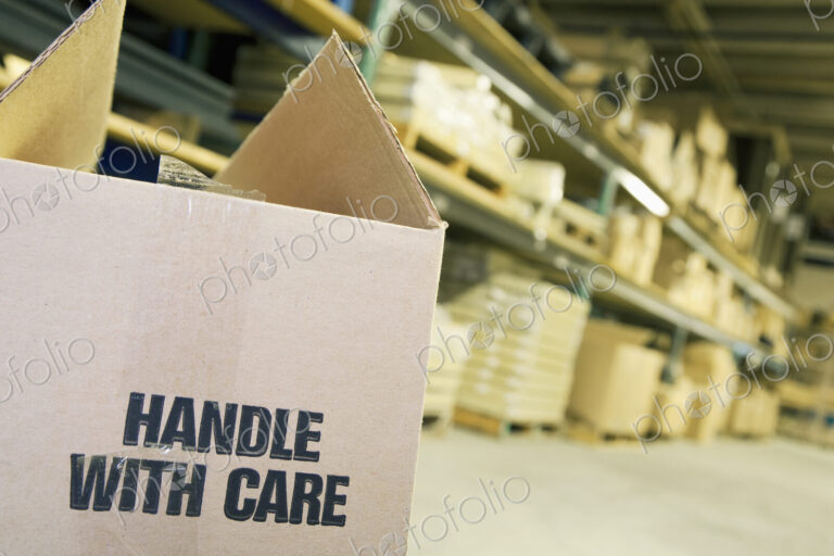 Carboard box in warehouse with shelves behind.